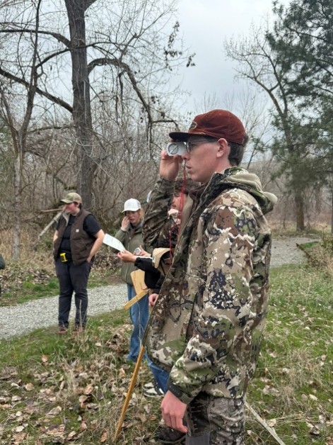 Student looking through mini range finder to determine DMH of trees at Forestry field day.