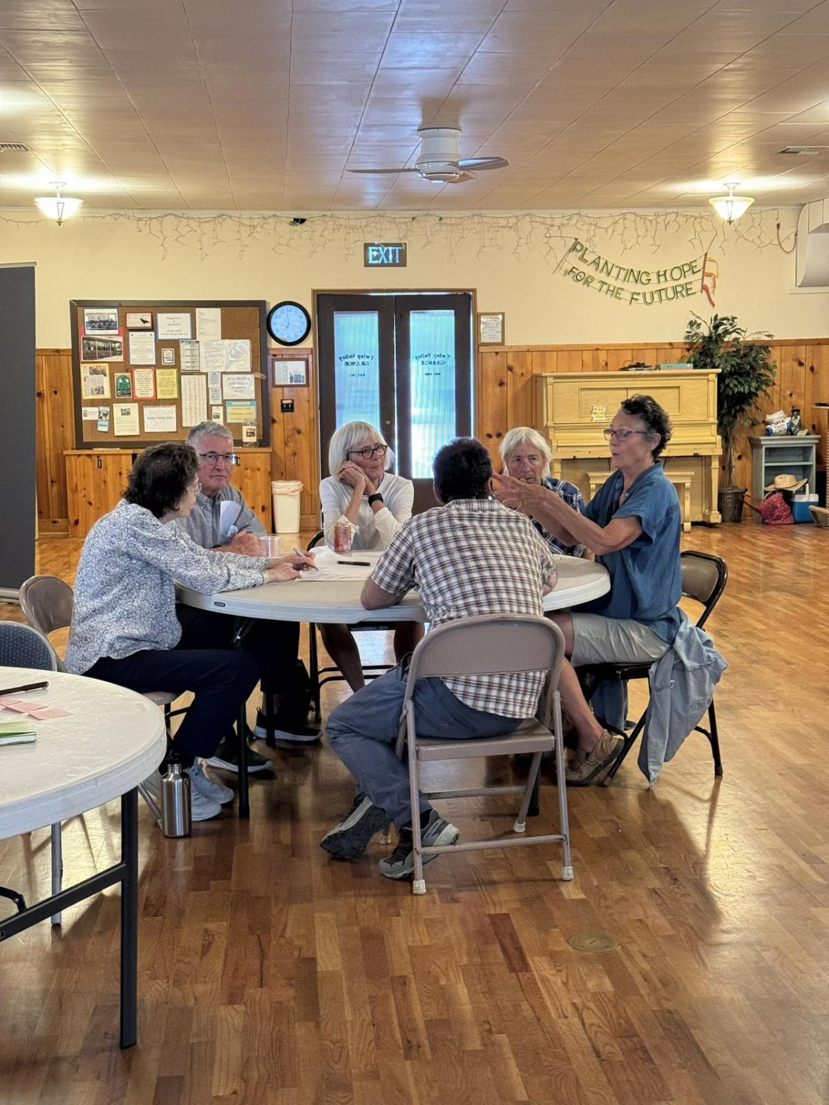 Five people sitting at a table having a discussion in a community room