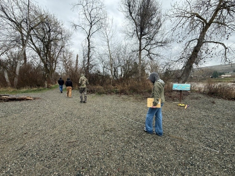 Students taking measurements, looking at the ground with a measuring tape at Forestry field day.