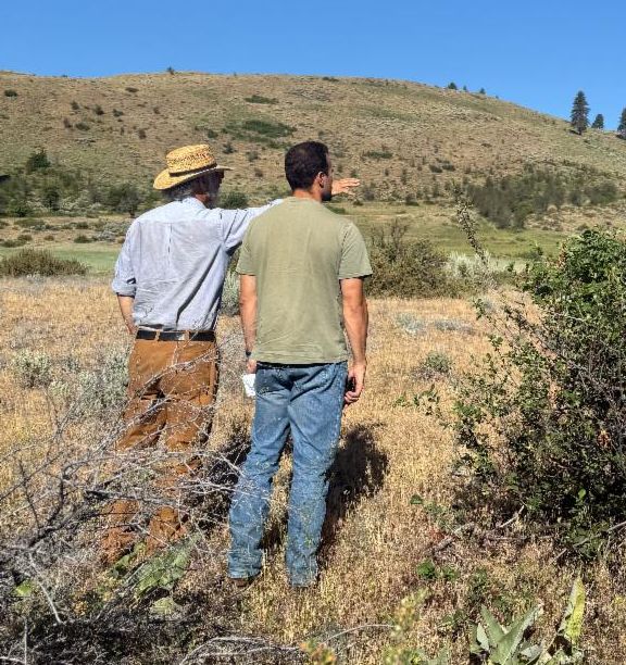 New staff member, Thomas, on a site visit with cooperator in a field. 