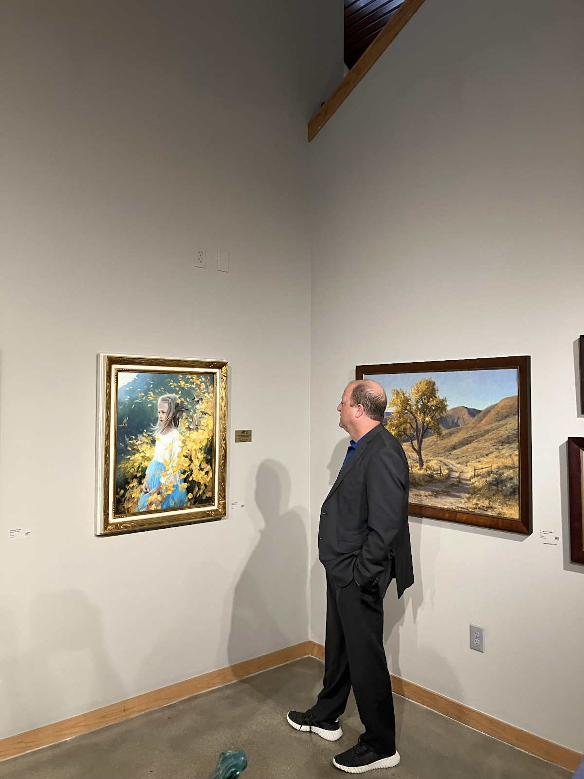 Governor Polis looks at a painting of a little girl in front of Aspen trees at the Governor's Art Show.