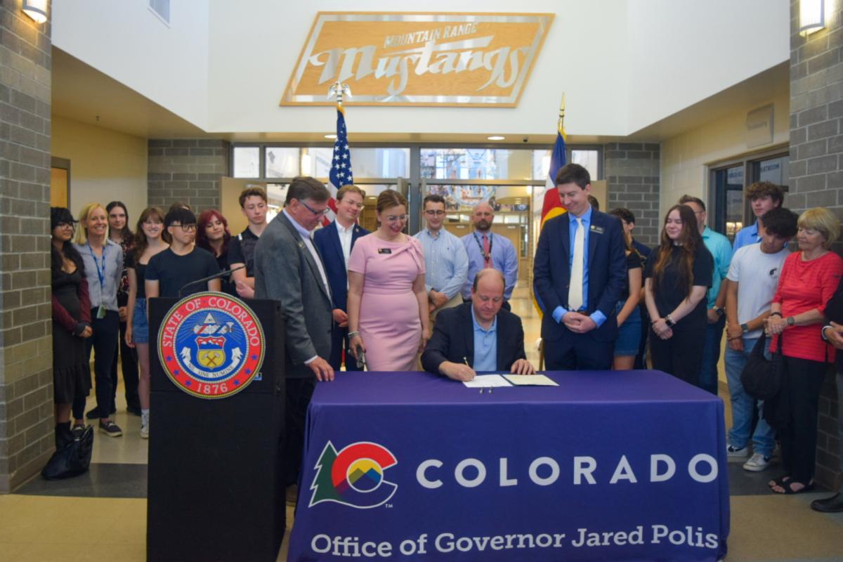 Educators, students, and legislators look on as Governor Polis signs HB24-1340 at Mountain Range High School.