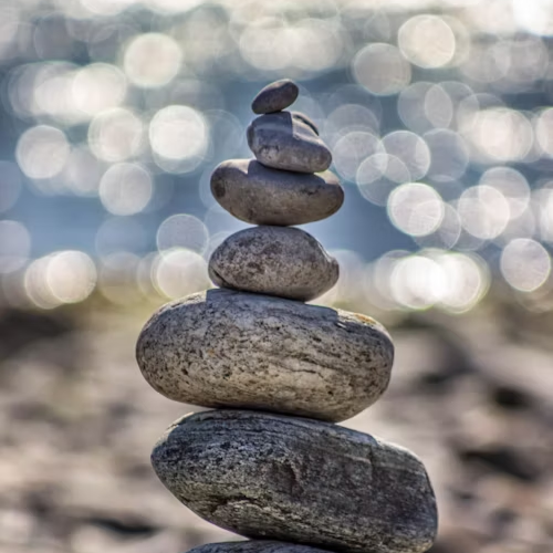 Stacked stones on a pebble beach with water in the background