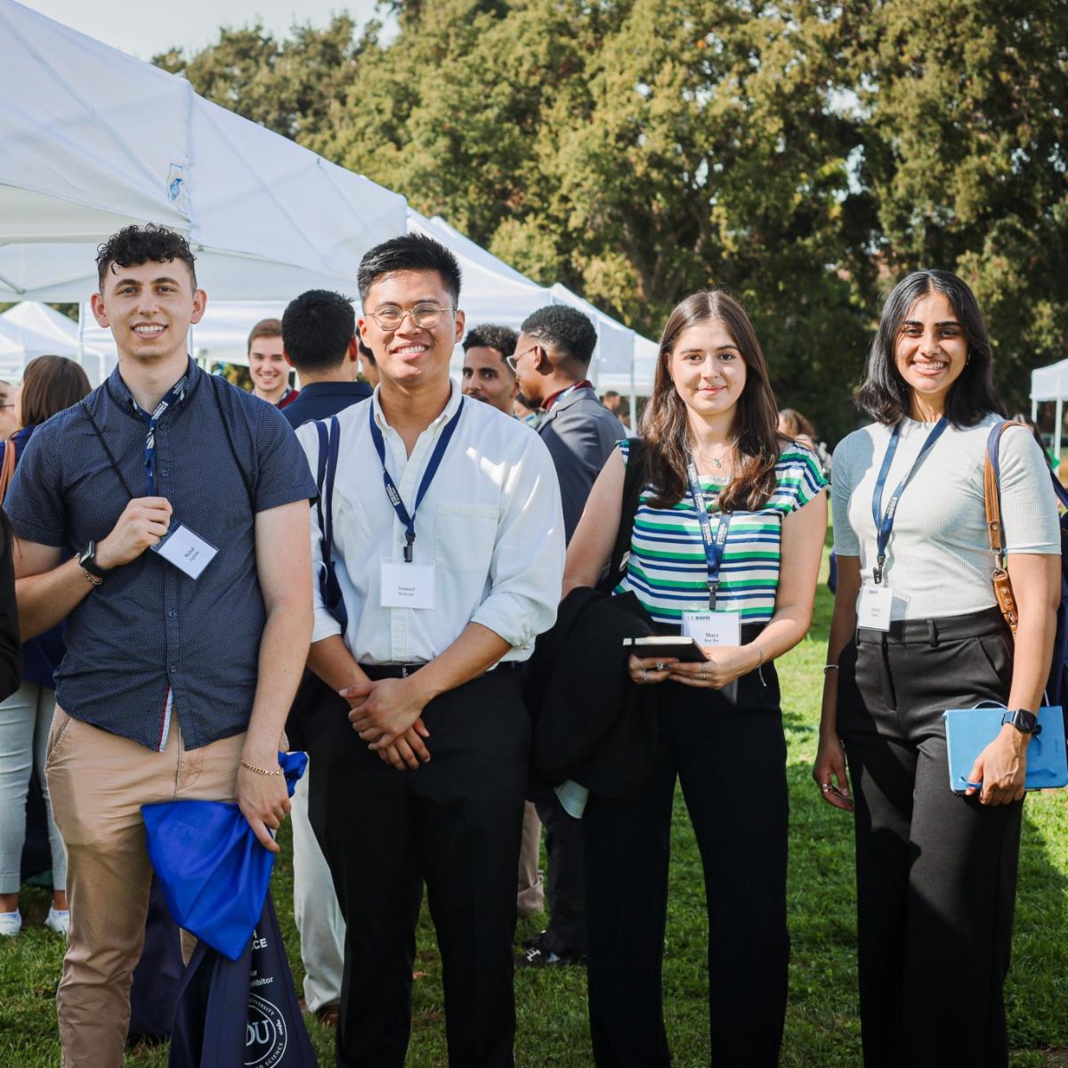 UC Davis students smiling outdoors wearing name badges at the annual Pre-Health Conference