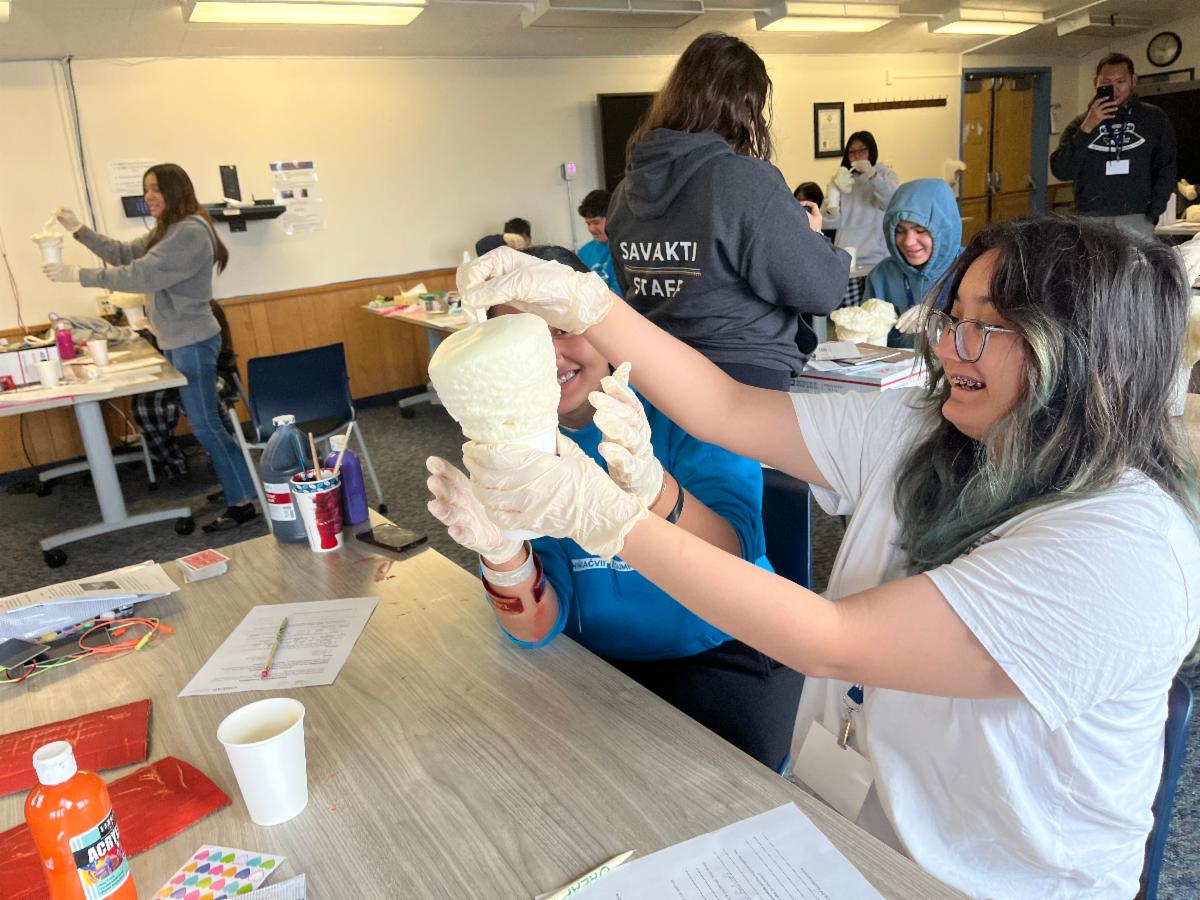 A smiling student builds a gnome shape out of foam
