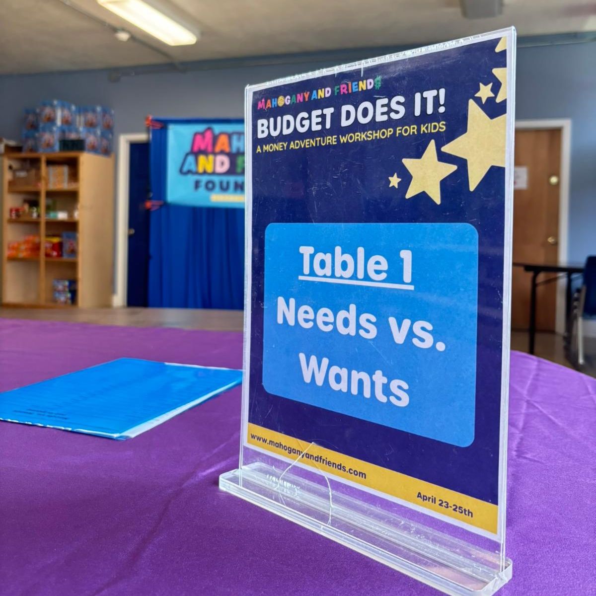 Table Signage with Needs vs Wants at Children's Financial Literacy Event