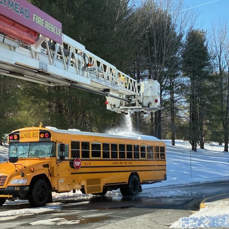 ACFR Assists ACPS with clearing snow from the tops of school buses during winter snow storm.