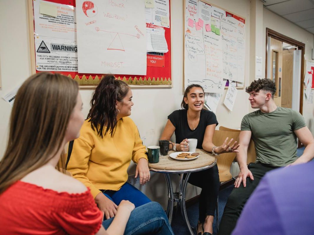 Four students sit around a table and talk