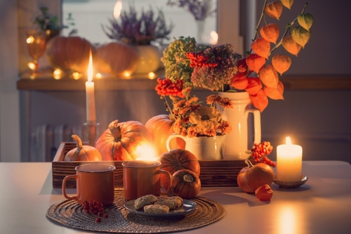 two orange cups  of tea and autumn decor with pumpkins_ flowers and burning candles on table