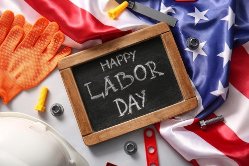Chalkboard with text HAPPY LABOR DAY_ USA flag and toy tools on blue background. Labor Day celebration