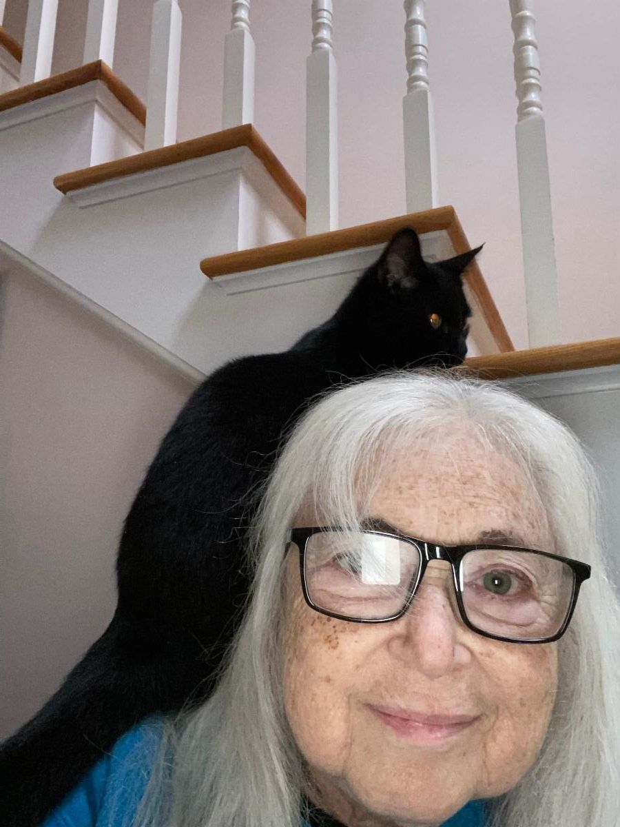Dr. Shelly Cohen with her black cat sitting on her back shoulder. 