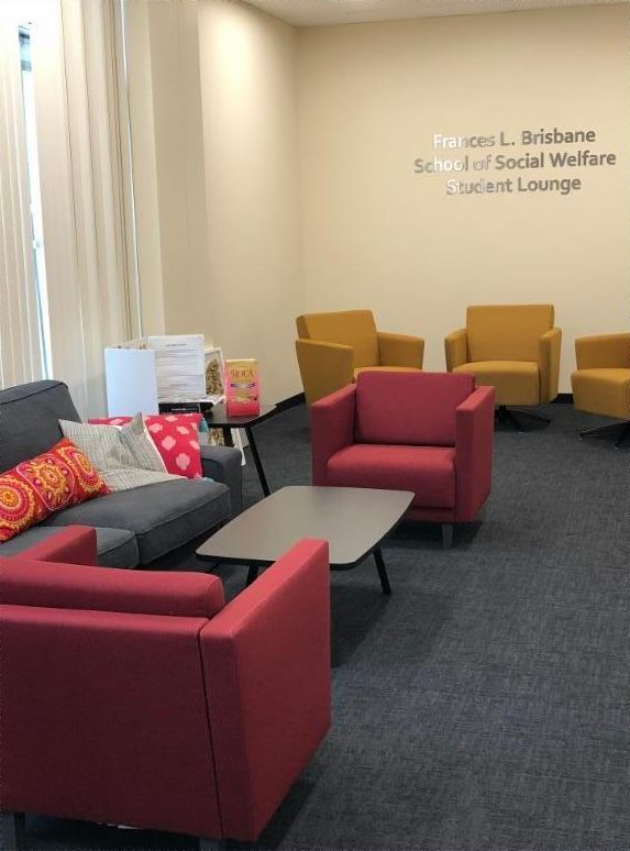 Red and yellow chairs placed around the room and a cozy gray couch with red and yellow throw pillows on it.
