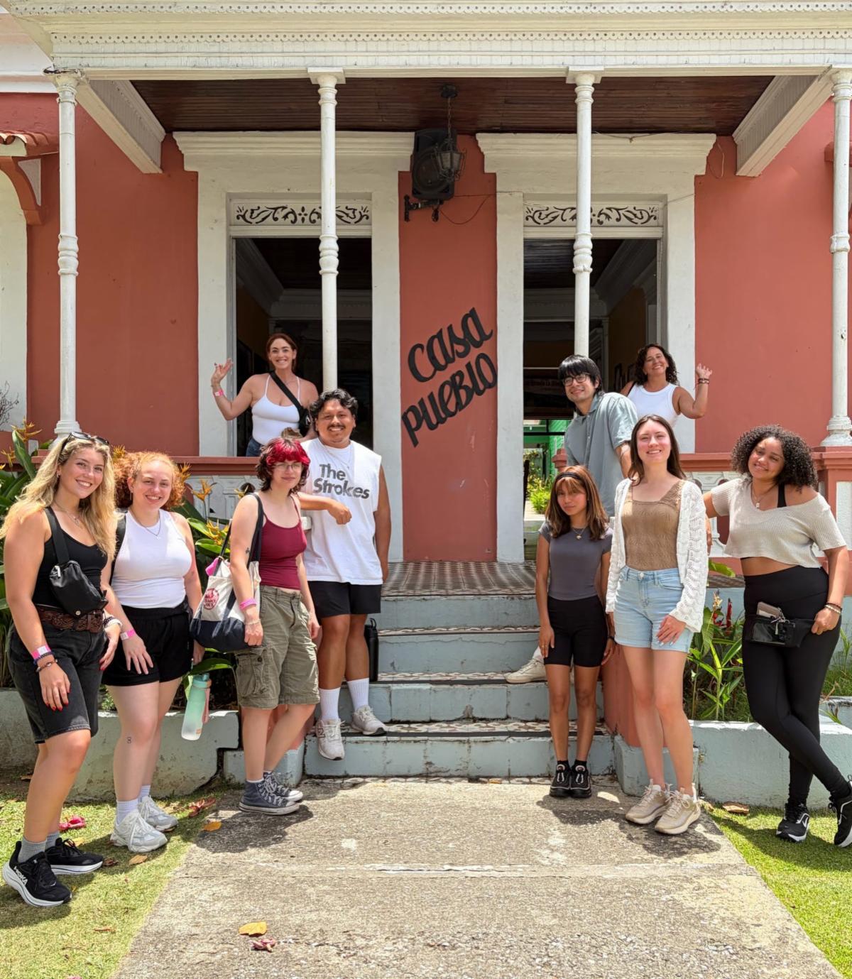 Various students standing in front of Casa Pueblo porch steps.