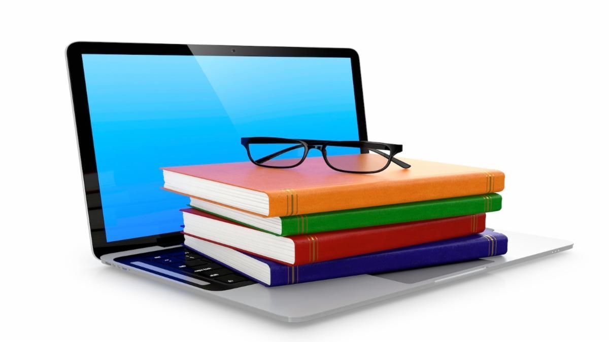 computer laptop with a stack of books and a pair of eyeglasses on top