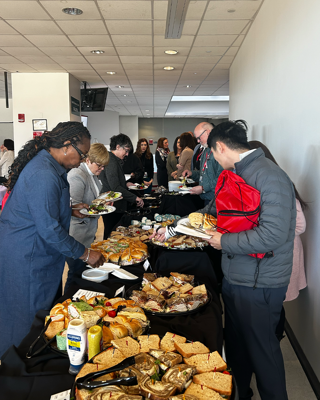 Several attendees helping themselves to a plentiful selection of sandwiches and wraps.