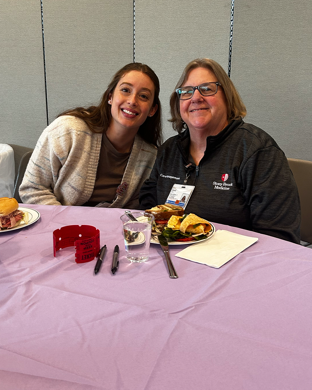 Two women sitting at a table smiling.