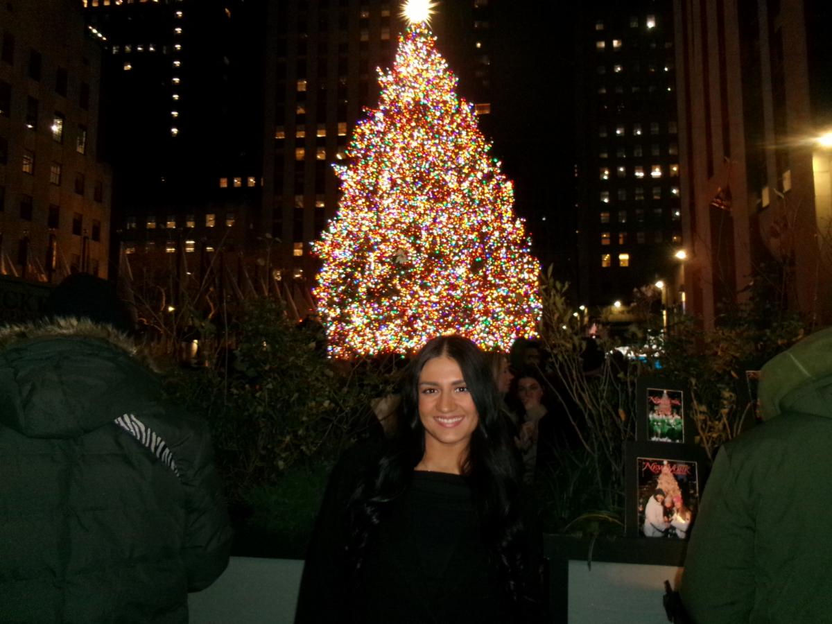 Student standing in front of a Christmas tree
