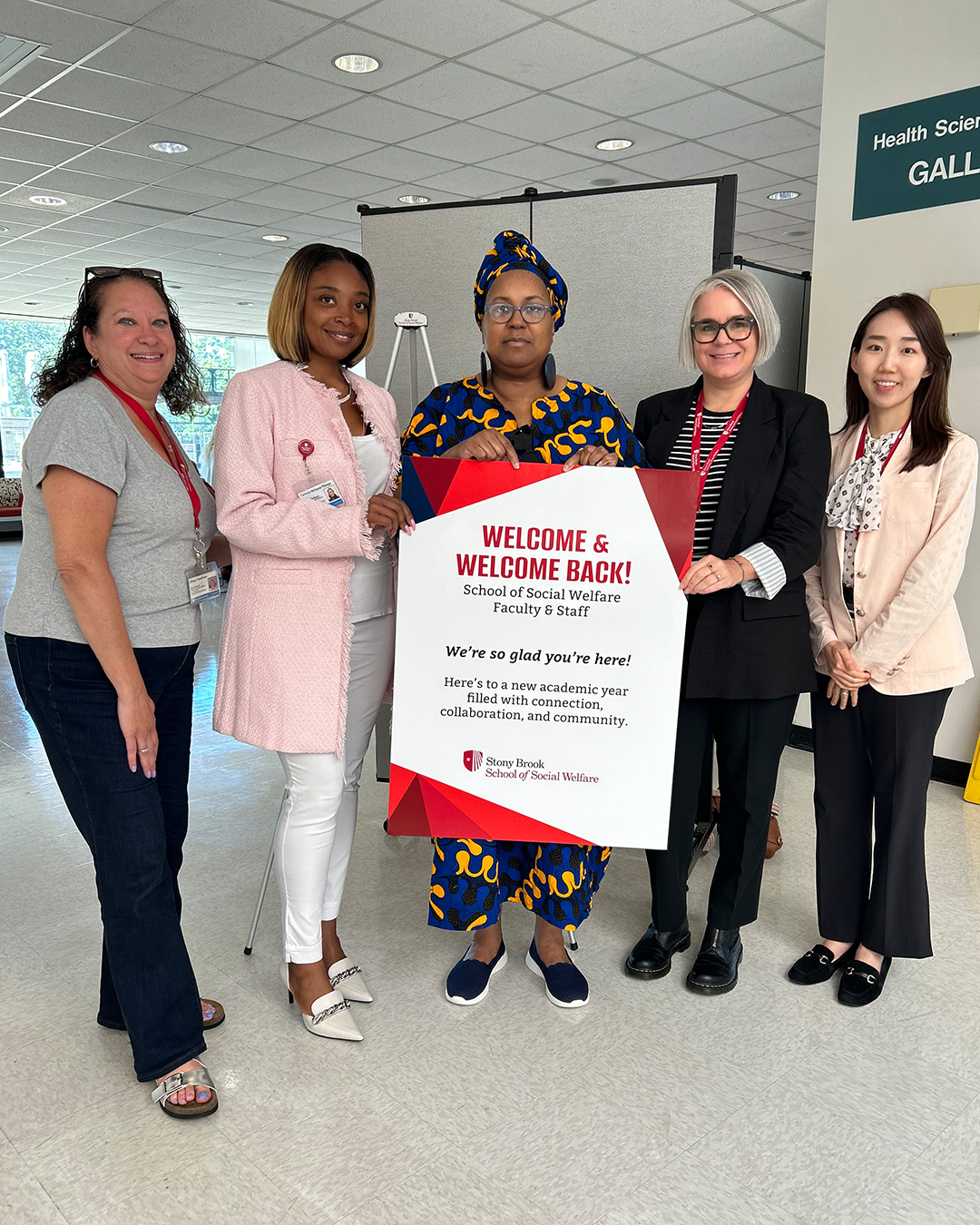 School of Social Welfare faculty posing with Welcome and Welcome Back poster.