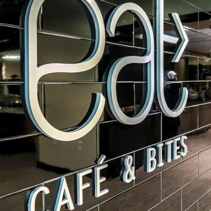 Entrance to eat Cafe and Bites with a large metallic letters on a glossy black tiled wall