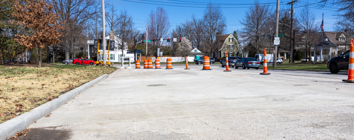 A view of one of the restored access shafts that were used to work on the Interceptor Restoration Project. The image shows a concrete road with an intersection and cars in the background, with construction barrels blocking the restored site.