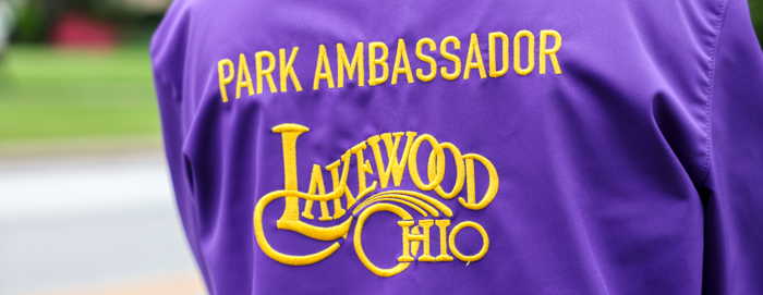 The back side of a park ambassador's jacket with embroidered yellow text that reads "Park Ambassador" with the Lakewood logo beneath it. Jacket is purple.