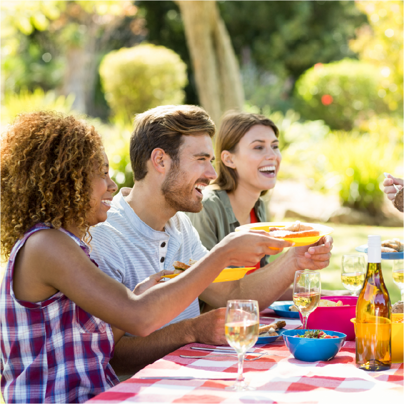 People having a picnic at a table outside on a sunny day.