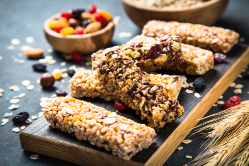 Granola bar with nuts_ fruit and berries on cutting board at dark stone table.