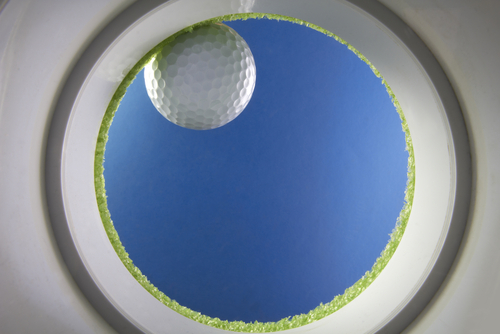 Golf ball drops into a cup on green_ shot from the bottom of the hole_ created  in studio