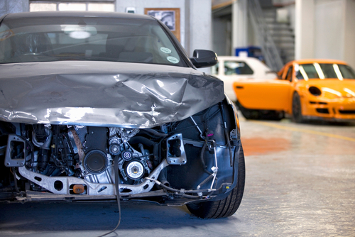 Front view of a damaged car after an accident in a garage.
