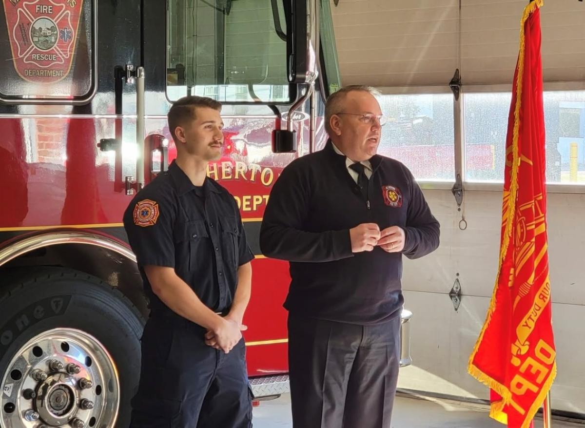 Firefighter Dakota Barnes being sworn in by Fire Chief John Ingram standing in front of fire truck