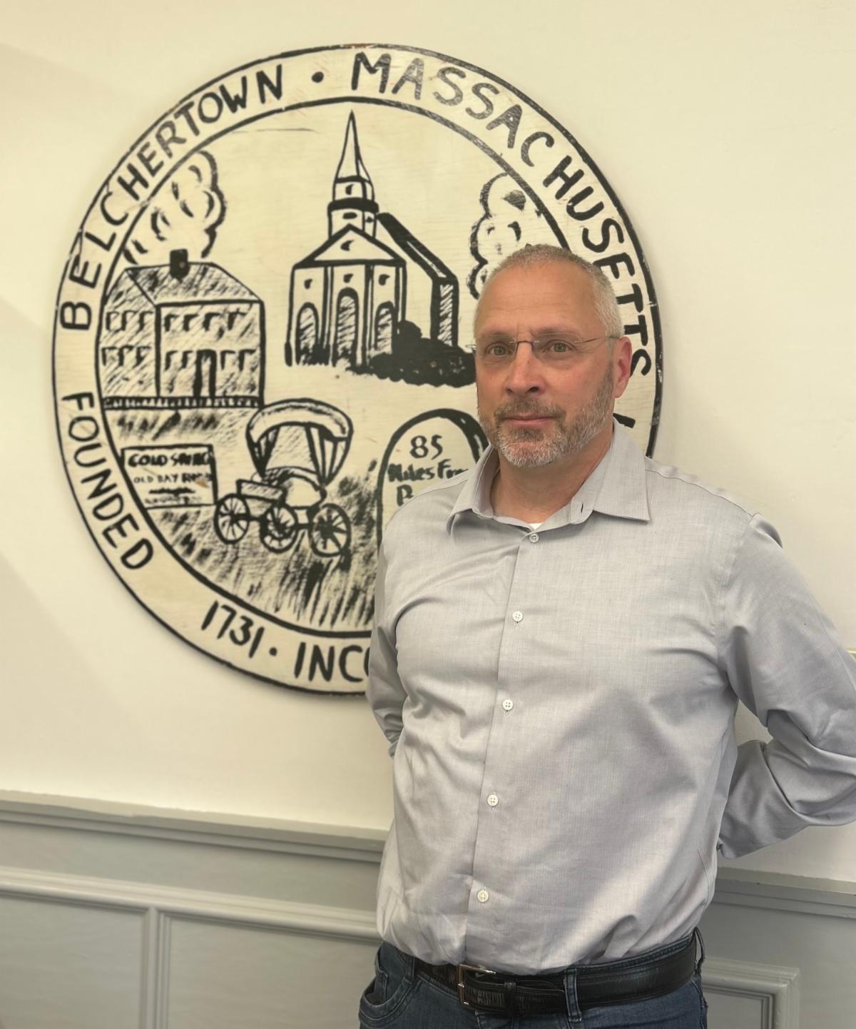 Town Manager Steve Williams posing for a picture in his office in front of the Town Seal