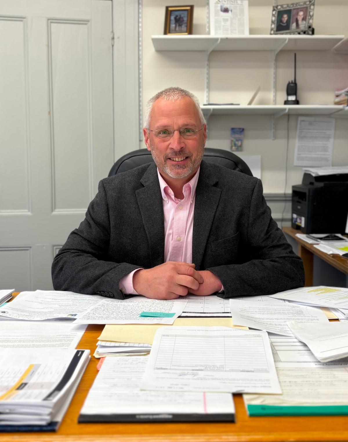 Town Manager Steve Williams sitting at his office desk surrounded by paperwork