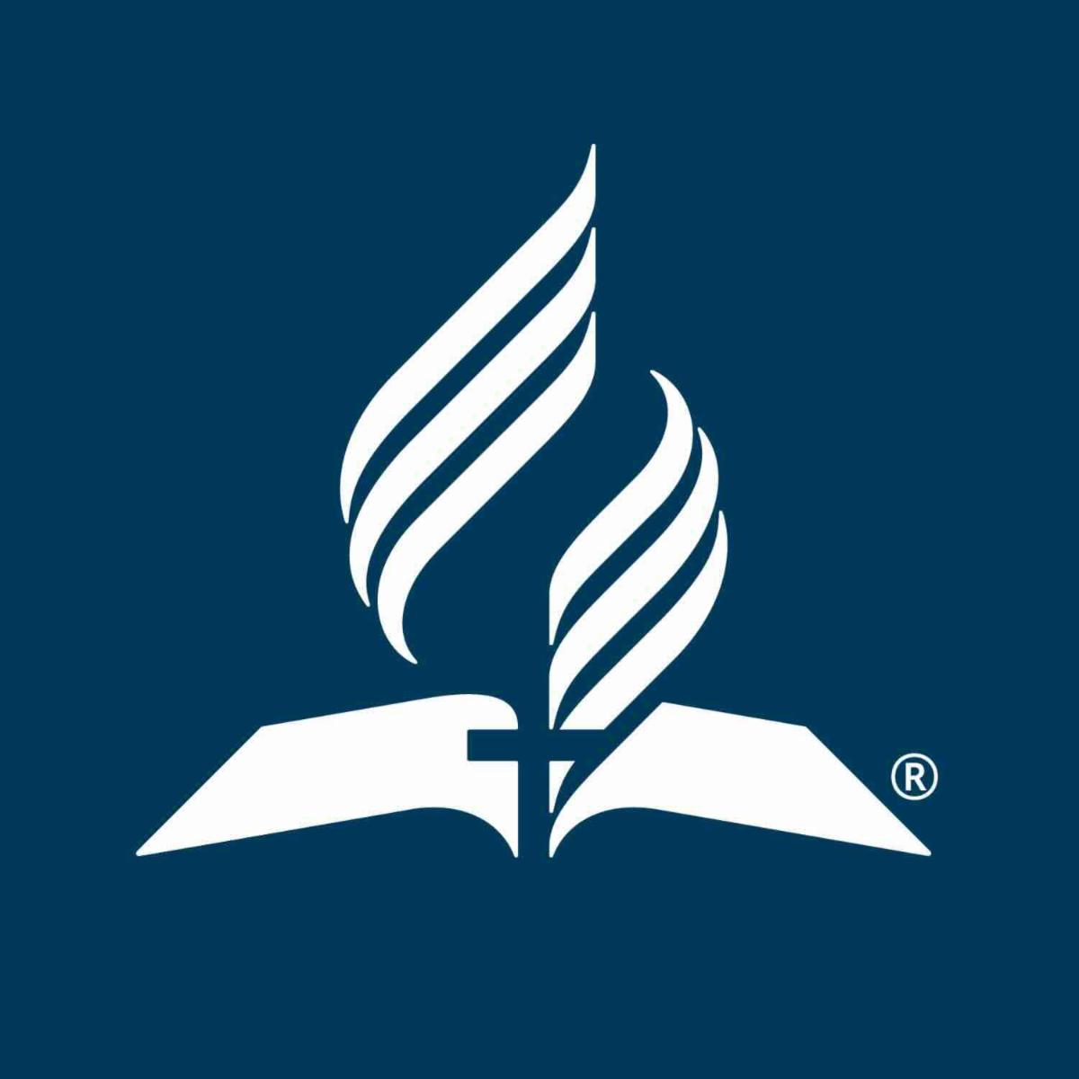 NAD Logo of an open bible in white with the deep blue cross at the center, a white encircling flame rising above the Bible. All on a deep blue background. 