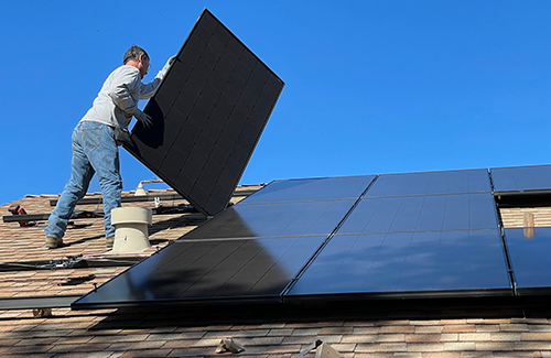 Photo by Bill Mead on Unsplash. Worker installing solar panels on a roof