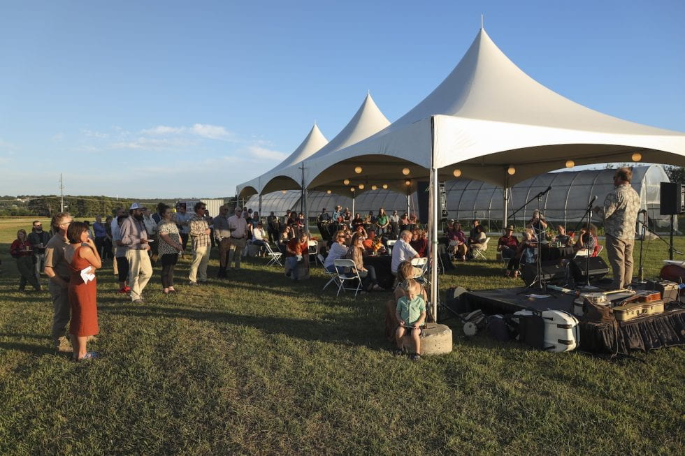 White tents against blue skies with people milling around and sitting at tables