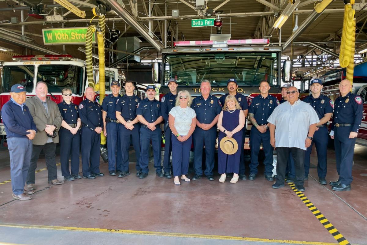 firefighters and community members stand with fire engine
