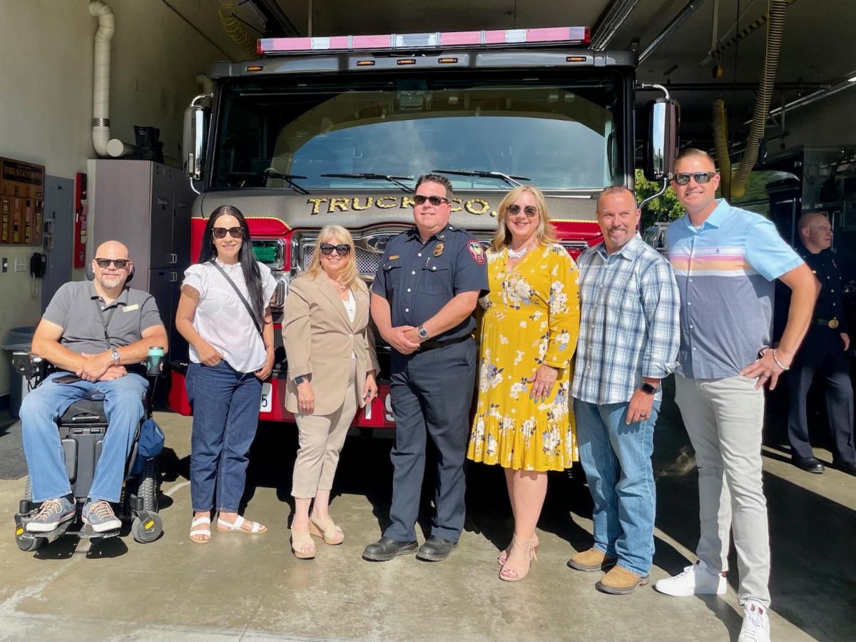 three women and four men stand in front of fire engine