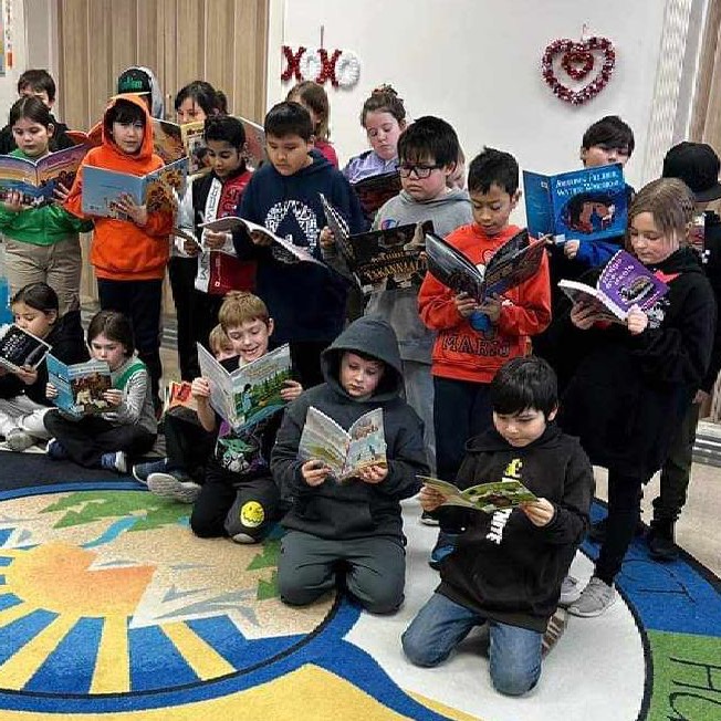Indigenous children reading books in a classroom.