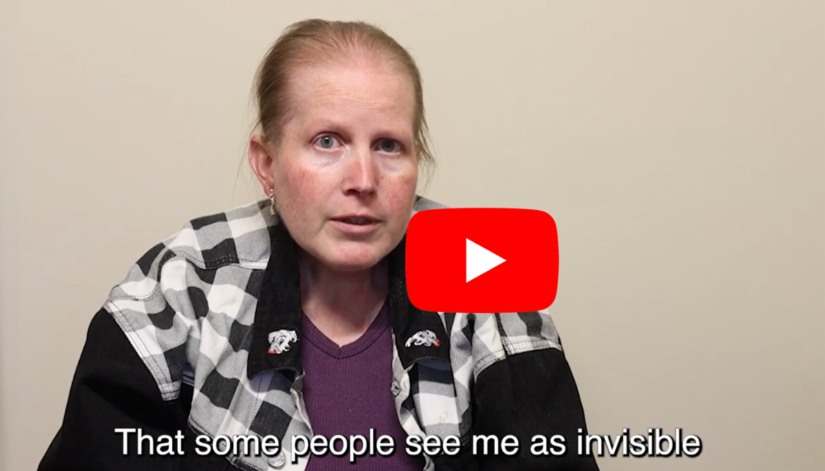A woman speaks directly to the camera in a video still. On-screen text reads, "That some people see me as invisible."