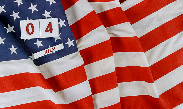 A closeup of an American flag with fabric folds showing red white and blue stripes with the number zero four and the word July displayed on top in block text format