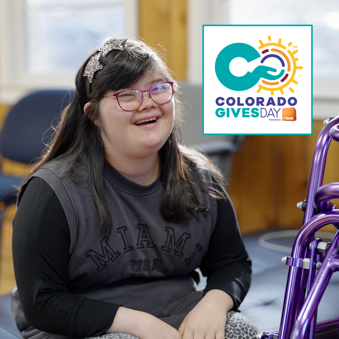 A smiling young girl with long dark hair and glasses sits indoors, wearing a gray âMiami USAâ shirt. A purple mobility device is beside her. In the top right corner is the Colorado Gives Day logo.