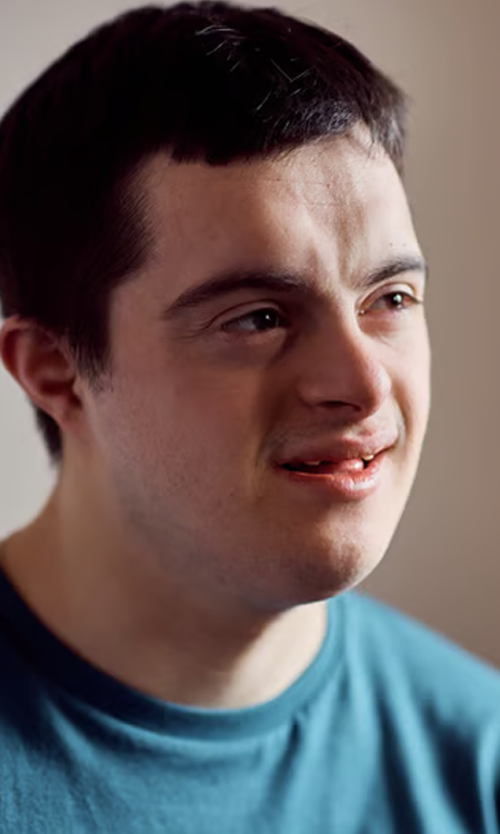 Close-up portrait of a young man smiling and looking to the side.