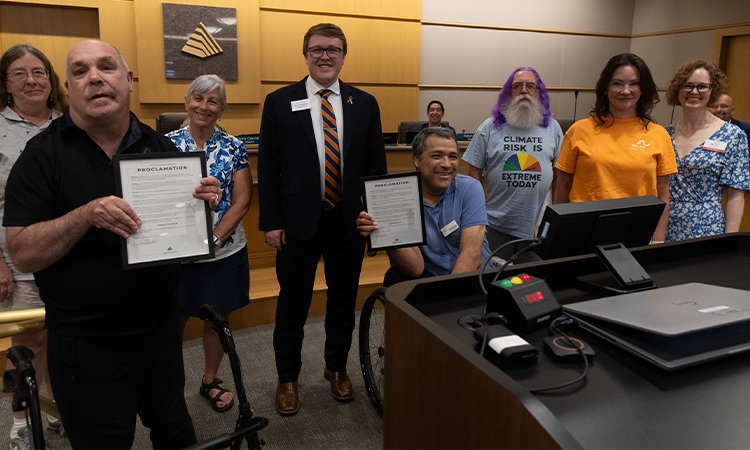 Group posing with two proclamations in a council chamber