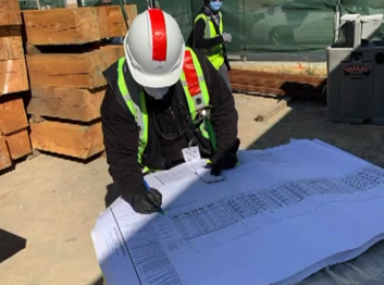 Photo of a building inspector on a construction site. He is looking at plans.