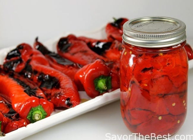 Roasted red cornos peppers on a platter and preserved in canning jar.