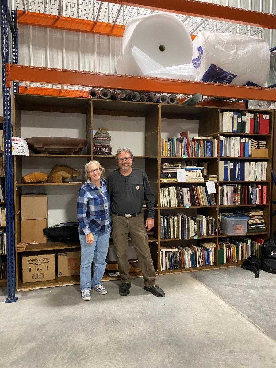 Photo of Marie and Mark Latta standing in front of shelves of art and boxes in a storage facility
