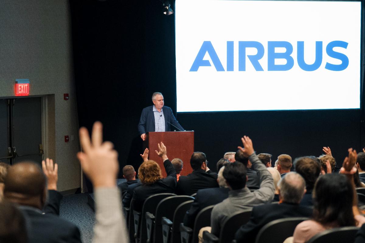 Airbus CEO Robin Hayes stands in front of a crowd of students, faculty and alumni.