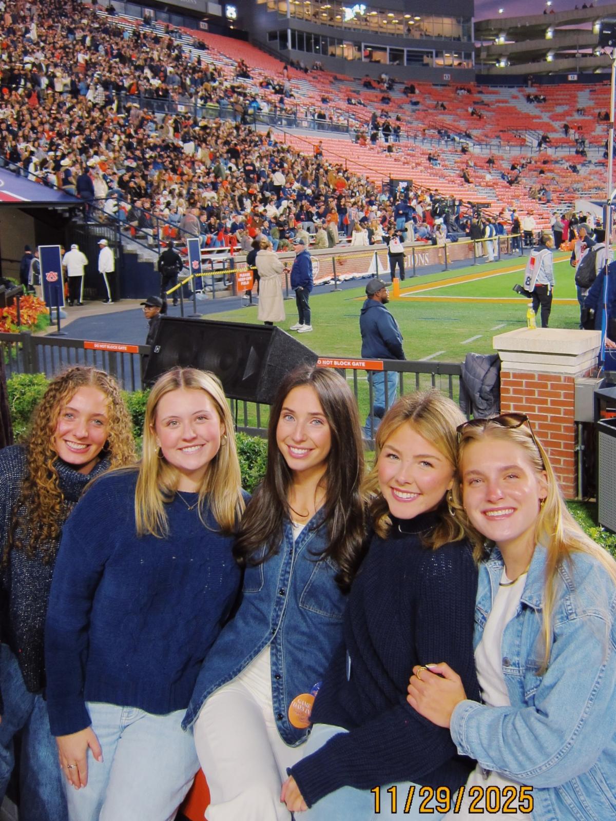 Senior members of the Auburn 99s smile at camera inside Jordan Hare Stadium front row
