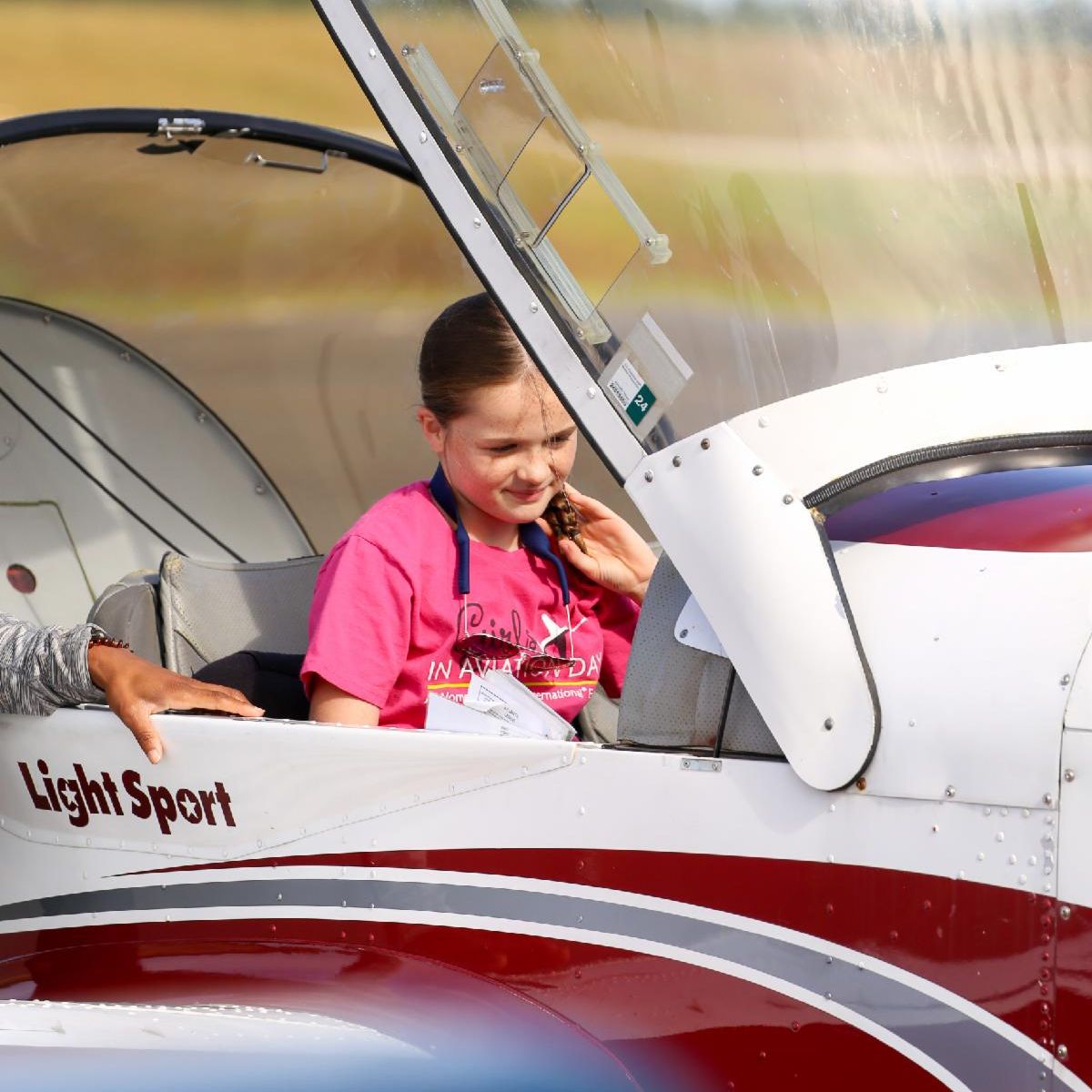 Two striped wing ambassadors stand in front of plane at Osh Kosh