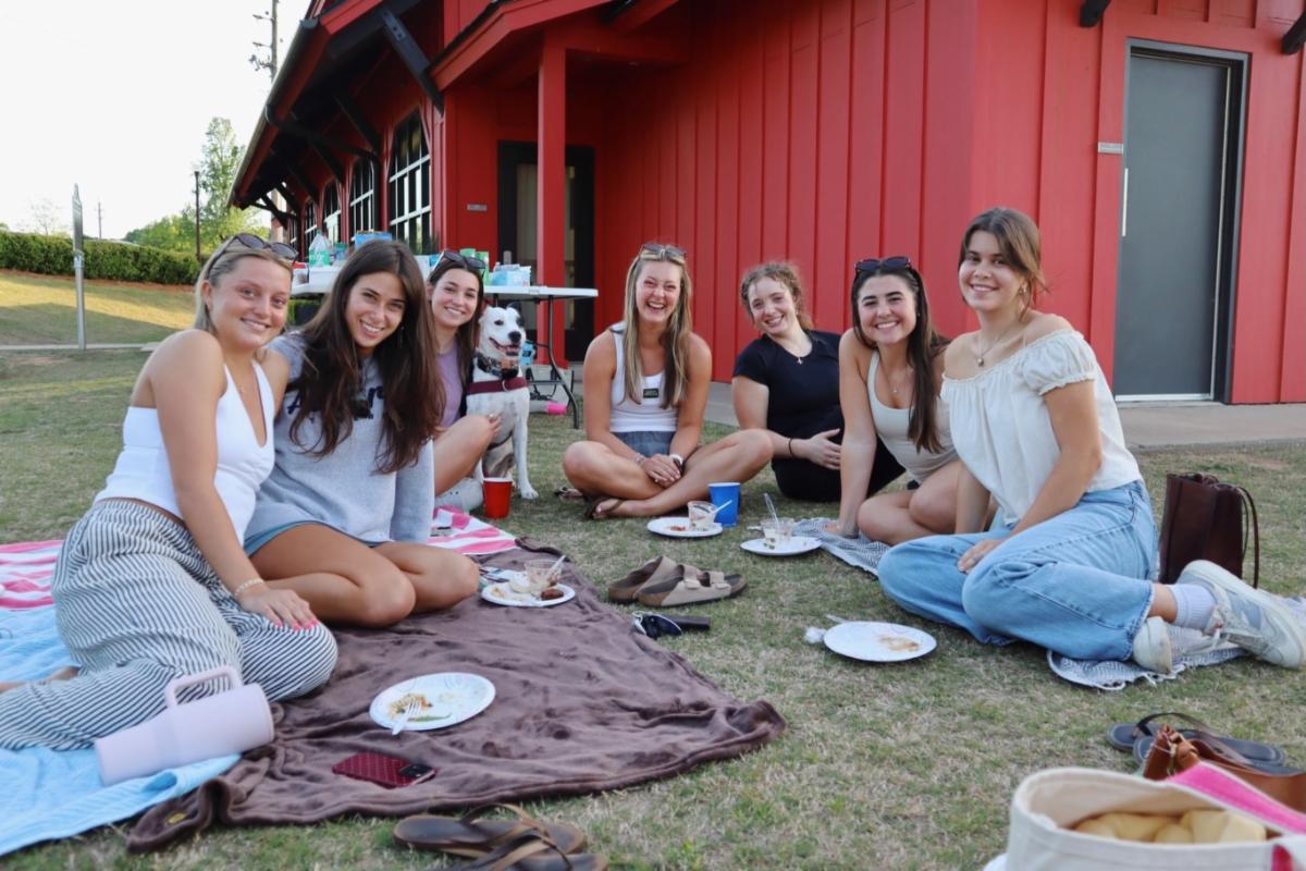 Ninety Nines sit on picnic blankets outside of the Red Barn